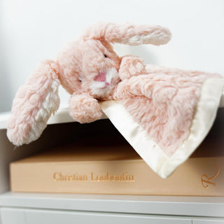 Pink plush bunny with a blanket on a shelf